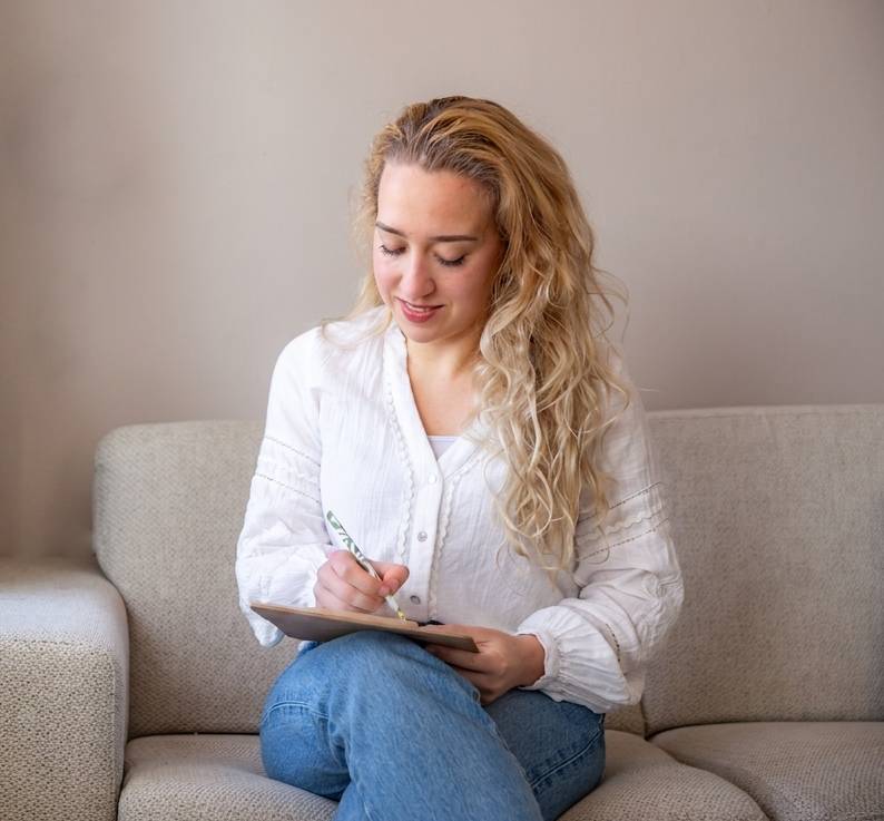 Lois zit op de bank en schrijft aandachtig in een notitieblok tijdens een sessie